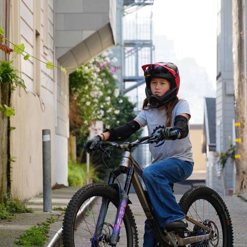 Emi on her bike on a city sidewalk