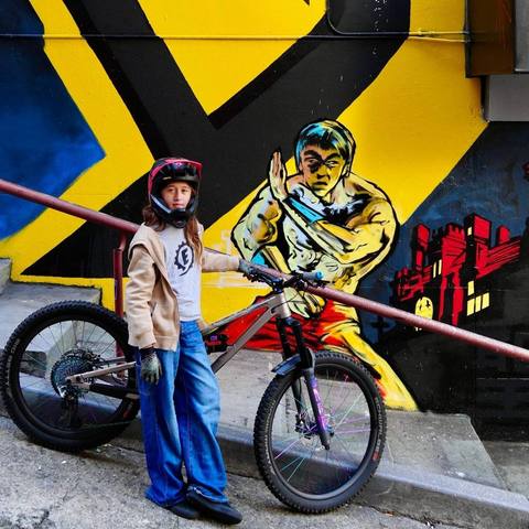 Emi with her bike in front of a mural