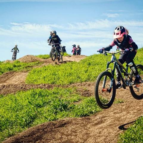 Emi riding a grassy dirt jump line